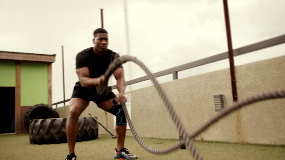 Athlete training with battle ropes while wearing the knee brace