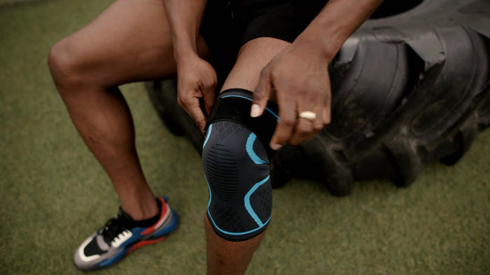 Athlete adjusting the knee brace while sitting on a tire